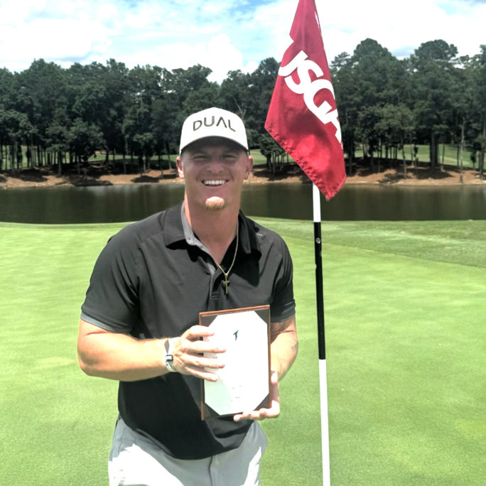 Evan Thompson holding a plaque standing next to a USGA flag