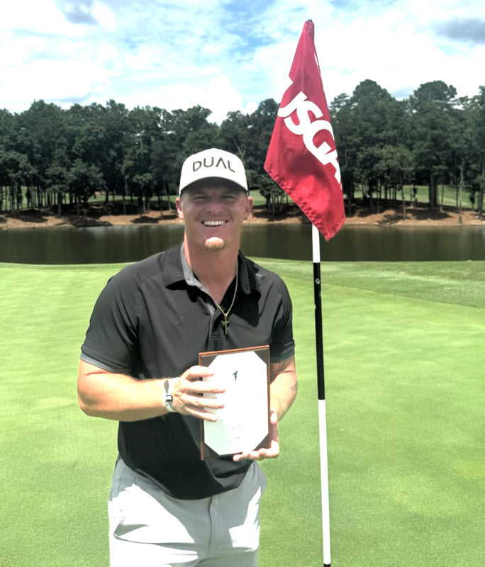 Evan Thompson holding a plaque standing next to a USGA flag